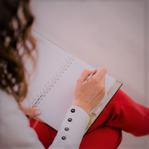 Auf dem Foto ist eine weibliche Person zu sehen, die etwas in ein Notizbuch schreibt. Auf dem Foto ist eine weibliche Person zu sehen, die etwas in ein Notizbuch schreibt.