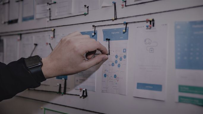 Das Bild zeigt eine Hand, die Informationen auf einer Wandtafel befestigt (Quelle: Alvaro Reyes - unsplash) Das Bild zeigt eine Hand, die Informationen auf einer Wandtafel befestigt