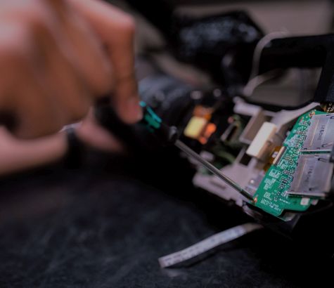 Das Bild zeigt eine Hand mit einem Schraubendreher an einem Gerät der Informationstechnik (Quelle: Unsplash | Raeng) Das Bild zeigt eine Hand mit einem Schraubendreher an einem Gerät der Informationstechnik