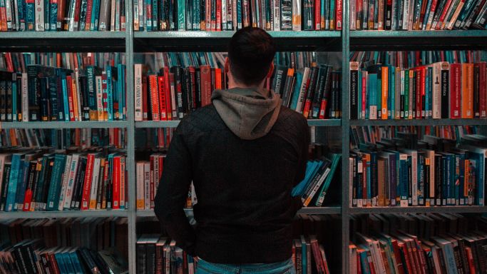 Das Bild zeigt einen Mann in einer Bibliothek
