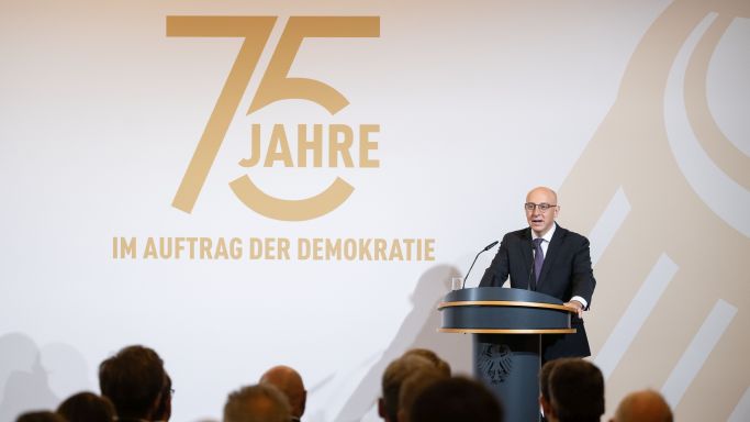 Das Bild zeigt Sinan Selen am Rednerpult beim Festakt 75 Jahre Bundesamt für Verfassungsschutz. (Quelle:  Laurin Schmid/bundesfoto) Das Bild zeigt Sinan Selen am Rednerpult beim Festakt 75 Jahre Bundesamt für Verfassungsschutz.