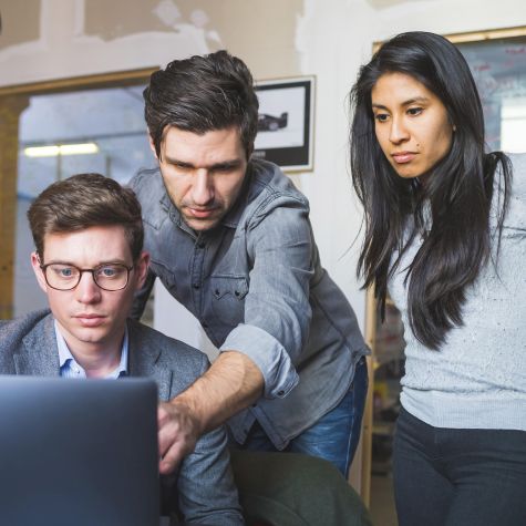 Die Aufnahme zeigt drei Arbeitskollegen im fachlichen Austausch, die in einem Büro gemeinsam einen Laptop betrachten (Quelle: Westend61 | Eugenio Marongiu/picture alliance) Die Aufnahme zeigt drei Arbeitskollegen im fachlichen Austausch, die in einem Büro gemeinsam einen Laptop betrachten
