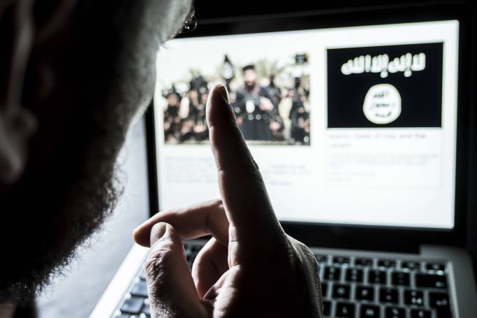 Eine Person mit erhobenem Zeigefinger vor einem Laptop, auf dem das Symbol des Islamischen Staats angezeigt wird (Quelle: IMAGO | Reporters) Eine Person mit erhobenem Zeigefinger vor einem Laptop, auf dem das Symbol des Islamischen Staats angezeigt wird