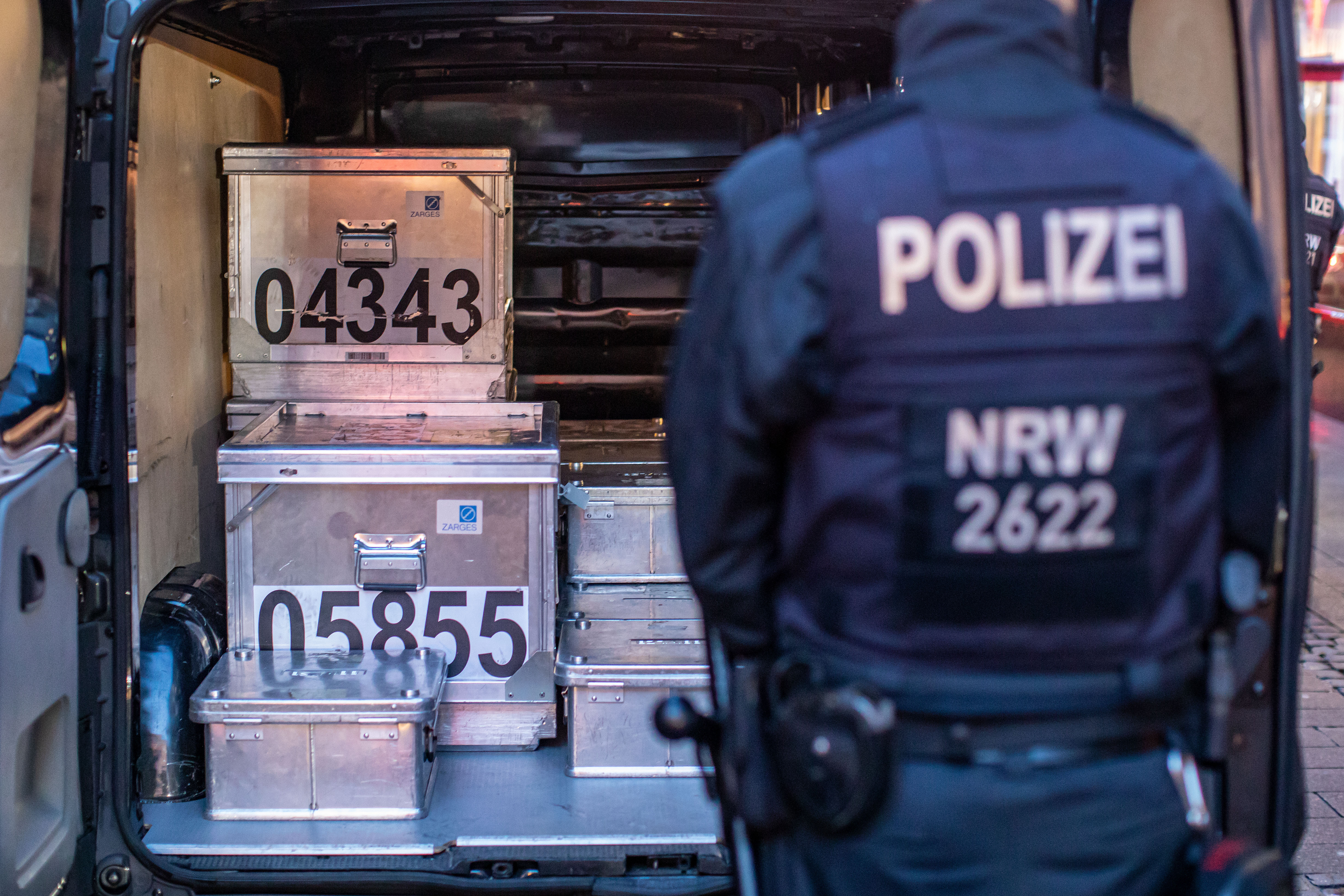 Die Aufnahme zeigt einen Polizeibeamten vor einem Transporter mit Metallkisten aus einer Beschlagnahmeaktion am 19.11.2019 in Duisburg
