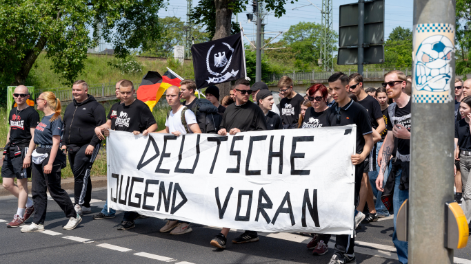 Eine Gruppe von Menschen marschiert mit einem Banner „DEUTSCHE JUGEND VORAN“. Sie tragen schwarze Kleidung und sind Teil einer Demonstration. (Quelle: picture alliance / PIC ONE | Bastian Stock) Eine Gruppe von Menschen marschiert mit einem Banner „DEUTSCHE JUGEND VORAN“. Sie tragen schwarze Kleidung und sind Teil einer Demonstration.