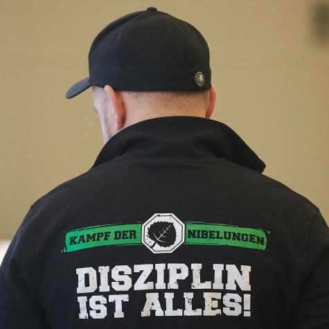 Die Aufnahme vom 26. Februar 2019 zeigt einen Angeklagten in der Rechtssache "Aktionsbüro Mittelrhein" im Landgericht Koblenz. Sein Sweatshirt trägt die Aufschrift "Kampf der Nibelungen - Disziplin ist alles!". (Quelle: picture alliance/dpa | Thomas Frey) Die Aufnahme vom 26. Februar 2019 zeigt einen Angeklagten in der Rechtssache "Aktionsbüro Mittelrhein" im Landgericht Koblenz. Sein Sweatshirt trägt die Aufschrift "Kampf der Nibelungen - Disziplin ist alles!".