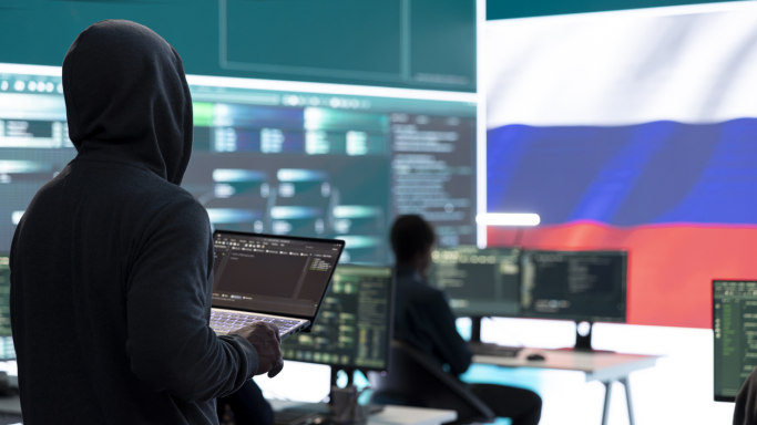 Die Abbildung zeigt Hacker in einem IT-Raum mit russischer Fahne. (Quelle: istock/Dragos Condrea) Die Abbildung zeigt Hacker in einem IT-Raum mit russischer Fahne.