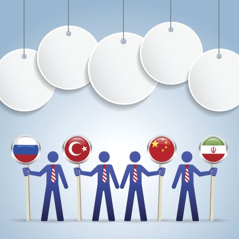 Die Aufnahme zeigt Papierfiguren in 3D-Optik, die die Länderflaggen von Russland, der Türkei, China und dem Iran halten