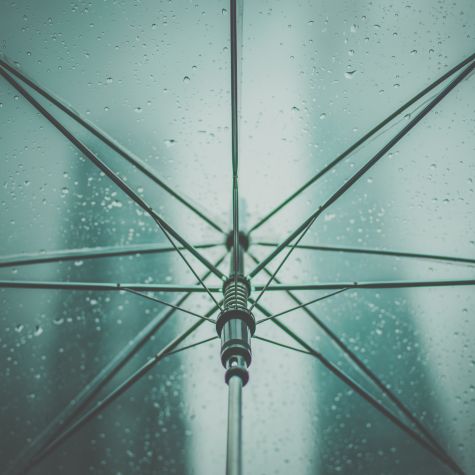 Die Aufnahme zeigt den Ausschnitt eines aufgespannten Regenschirms, der vor Regen schützt (Quelle: Photo by Shade Jay on Unsplash) Die Aufnahme zeigt den Ausschnitt eines aufgespannten Regenschirms, der vor Regen schützt