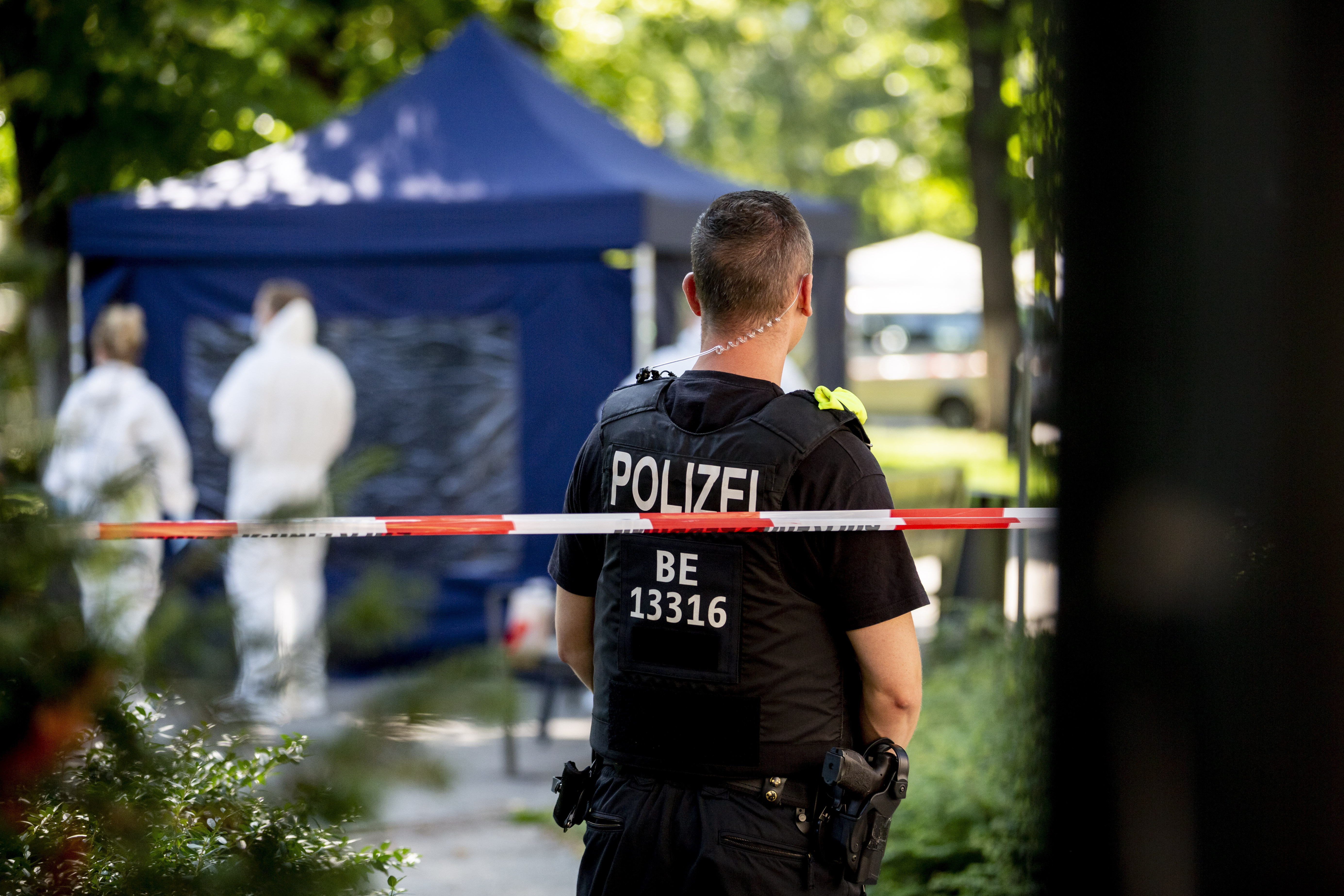 Die Aufnahme zeigt den Tatort des Tiergartenmords mit einem Polizisten im Vordergrund (Quelle: picture alliance | dpa | Christoph Soeder) Die Aufnahme zeigt den Tatort des Tiergartenmords mit einem Polizisten im Vordergrund