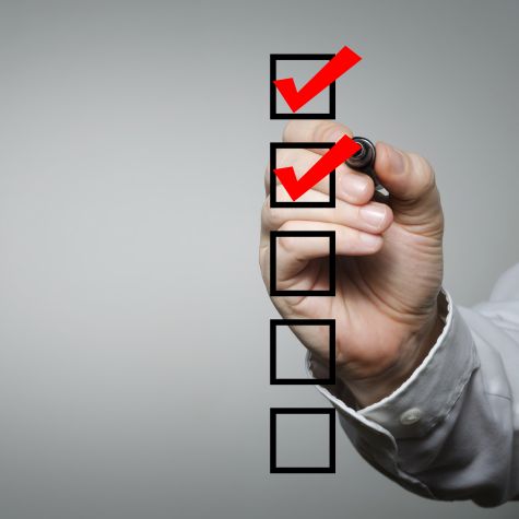 Die Aufnahme zeigt eine männliche Hand, die mit einem Rotstift eine im Vordergrund liegende Checkliste bearbeitet (Quelle: natasaadzic / iStock / Getty Images Plus) Die Aufnahme zeigt eine männliche Hand, die mit einem Rotstift eine im Vordergrund liegende Checkliste bearbeitet