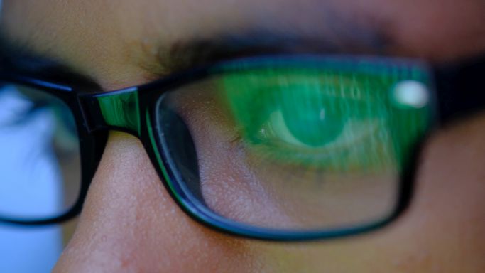 Das Bild zeigt den Ausschnitt eines männlichen Gesichts mit Brille, in dessen Gläsern sich ein binärer Code reflektiert (Quelle: Towfiqu Photography/Gettyimages) Das Bild zeigt den Ausschnitt eines männlichen Gesichts mit Brille, in dessen Gläsern sich ein binärer Code reflektiert