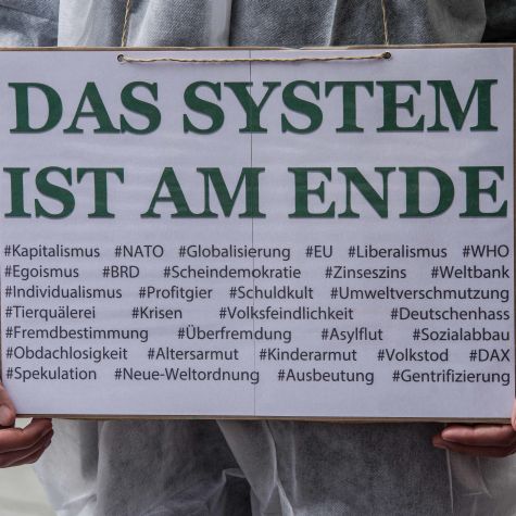 Die Aufnahme vom 1. Mai 2020 in München zeigt einen Mann, der im Rahmen einer Demonstration ein Schild mit der Aufschrift "Das System ist am Ende" hält.