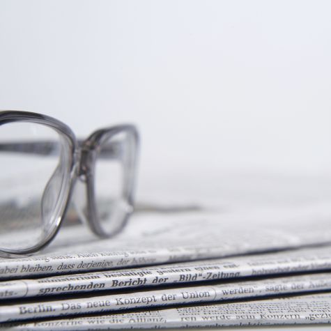 Die Aufnahme zeigt einen Stapel Zeitungen vor einem weißen Hintergrund, auf dem eine Brille liegt. (Quelle: Westend61/picture alliance) Die Aufnahme zeigt einen Stapel Zeitungen vor einem weißen Hintergrund, auf dem eine Brille liegt.