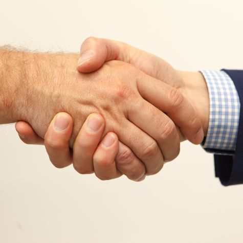 The shot shows a handshake between two men in closeup