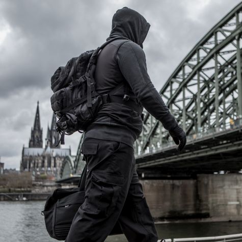 The shot shows a plainly dressed man in a hoodie, who wants to remain unidentified, carrying a travel bag on a riverbank