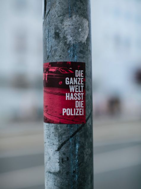 The shot shows a poster pasted on a pole with the inscription "The whole world hates the police" 