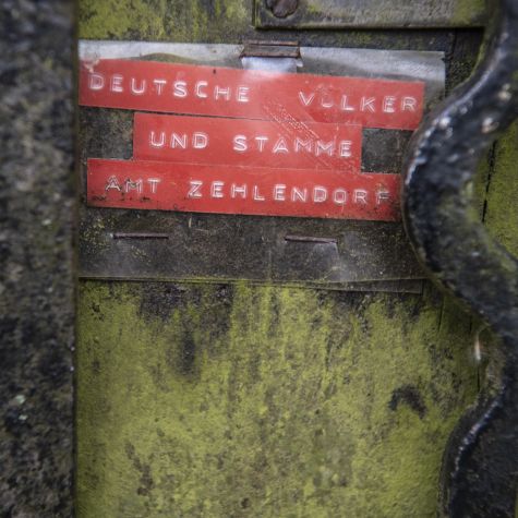 The photograph taken on March 19, 2020 shows a sign with the inscription "Geeinte deutsche Völker und Stämme - Amt Zehlendorf" (United German Peoples and Tribes - Zehlendorf Office) on a mailbox in front of a residential building in Berlin.